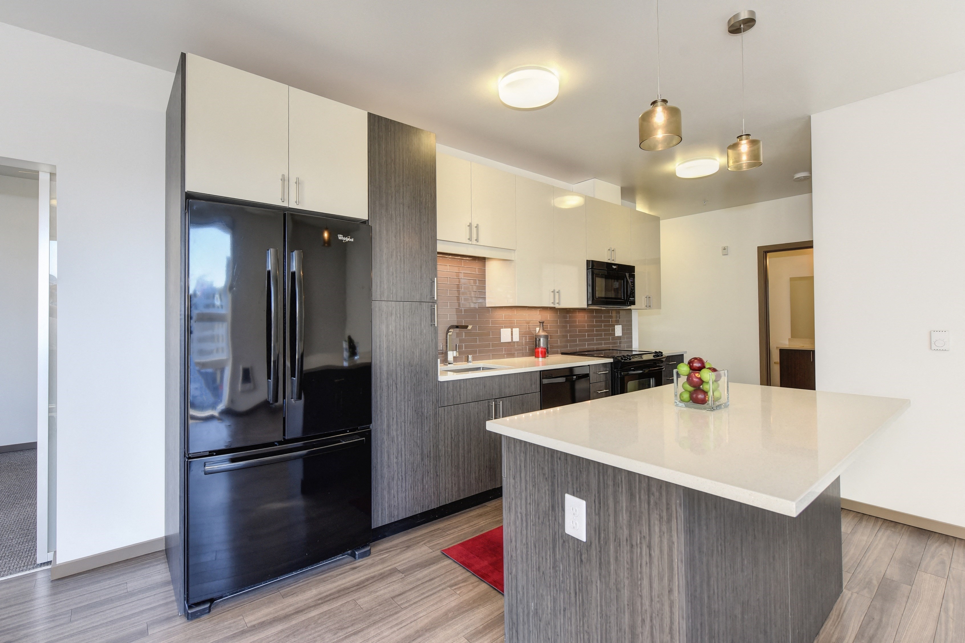 Kitchen with Hardwood Inspired Floor, Refrigerator, Gray Cabinents, Microwave and Bowl of Green/Red Apples